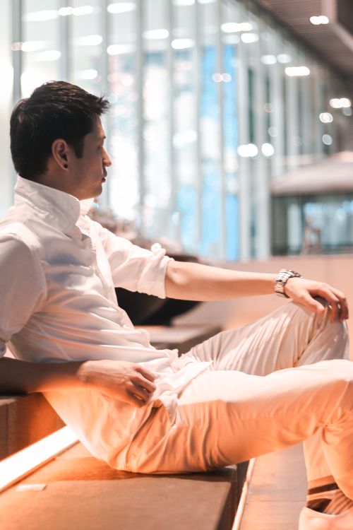 Free Asian man in white outfit posing on modern urban stairs in Seoul at night. Stock Photo