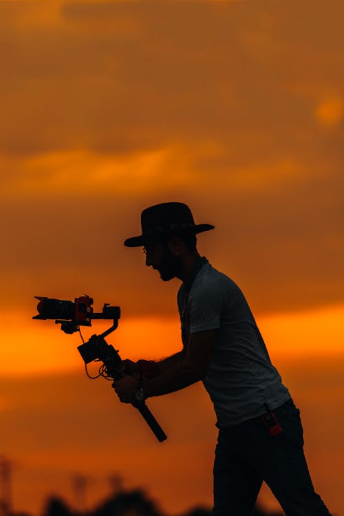 Ilmainen kuvapankkikuva tunnisteilla auringonlasku, cowboyhattu, kamera