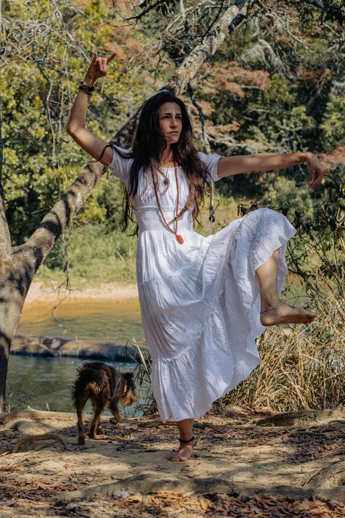 Free A woman in a white dress dances gracefully by a river in a natural setting. Celebrate freedom. Stock Photo