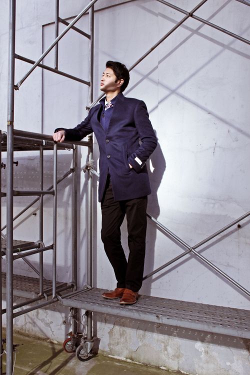 Free A stylish man in a navy suit poses on scaffolding in Seoul, South Korea, showcasing urban elegance. Stock Photo