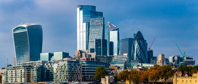 The modern financial skyline of London, featuring iconic glass skyscrapers along the River Thames under a bright blue sky.