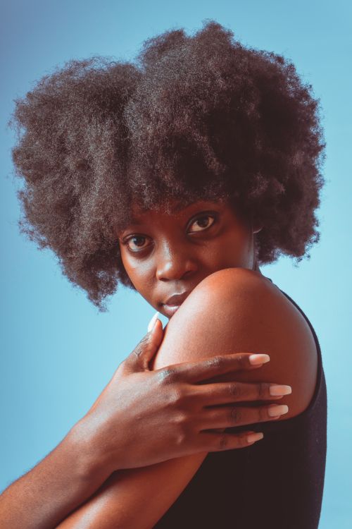 Free Striking studio portrait of a woman with afro hair against a blue background. Stock Photo