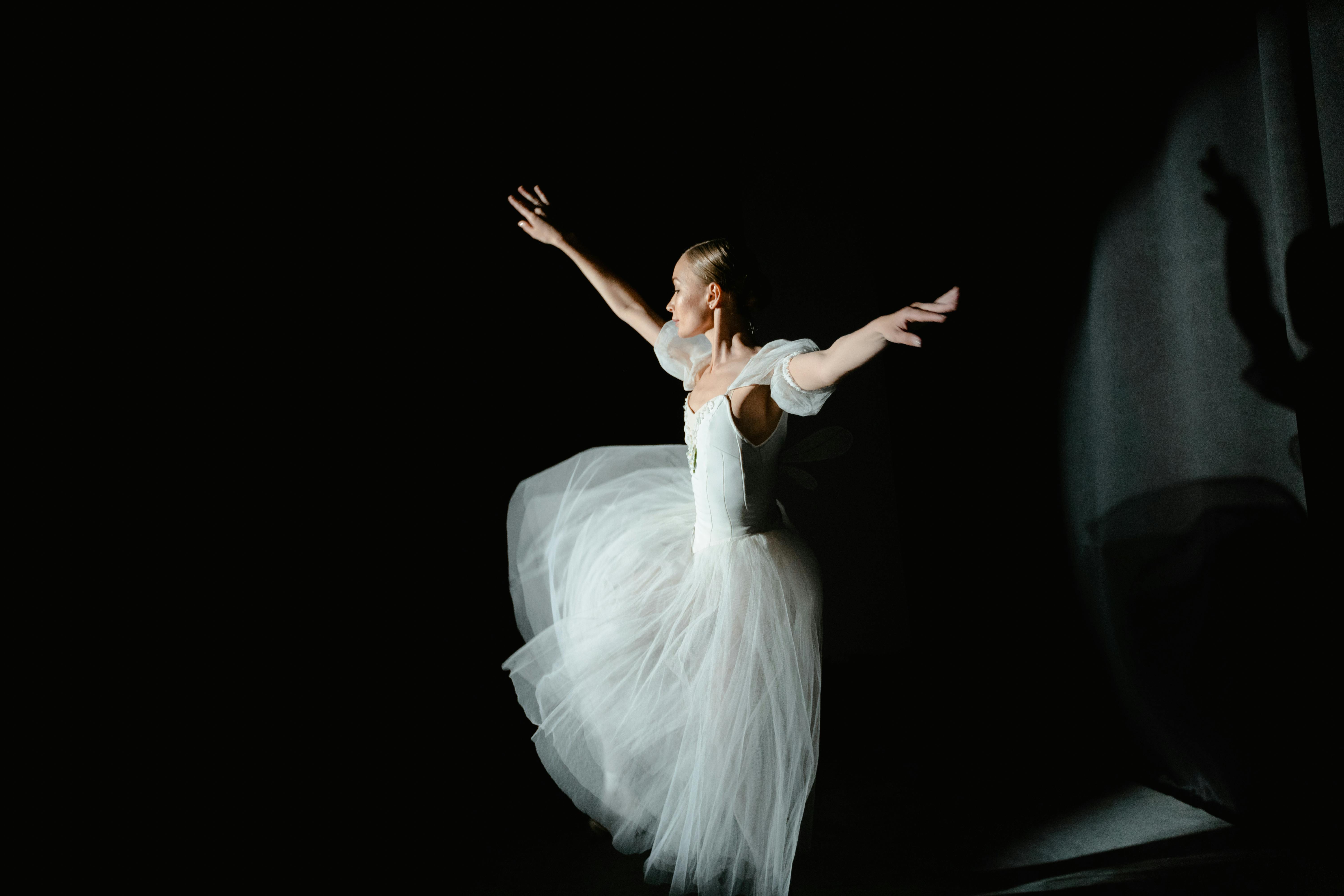 A professional ballerina elegantly performing a dance routine in a studio spotlight.