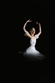 Graceful ballerina in white tutu dancing against a dark background, showcasing elegance and talent.