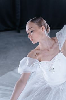 Graceful ballerina captured in mid-performance with an elegant white dress in a classic ballet pose.
