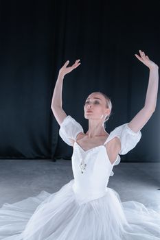 Graceful ballet dancer in white dress performing indoors with elegance and poise.
