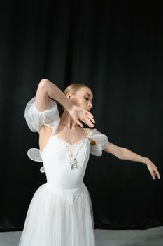 Elegant ballerina dancing in a classic white dress, captured in a studio setting.