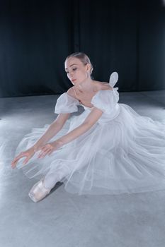 Elegant ballerina in white tutu gracefully posing in dance studio.