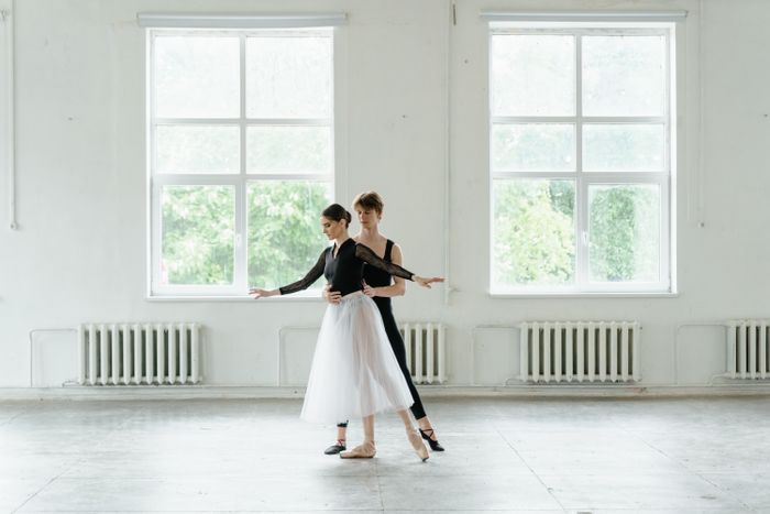 Dance partners rehearsing a lift in a bright studio