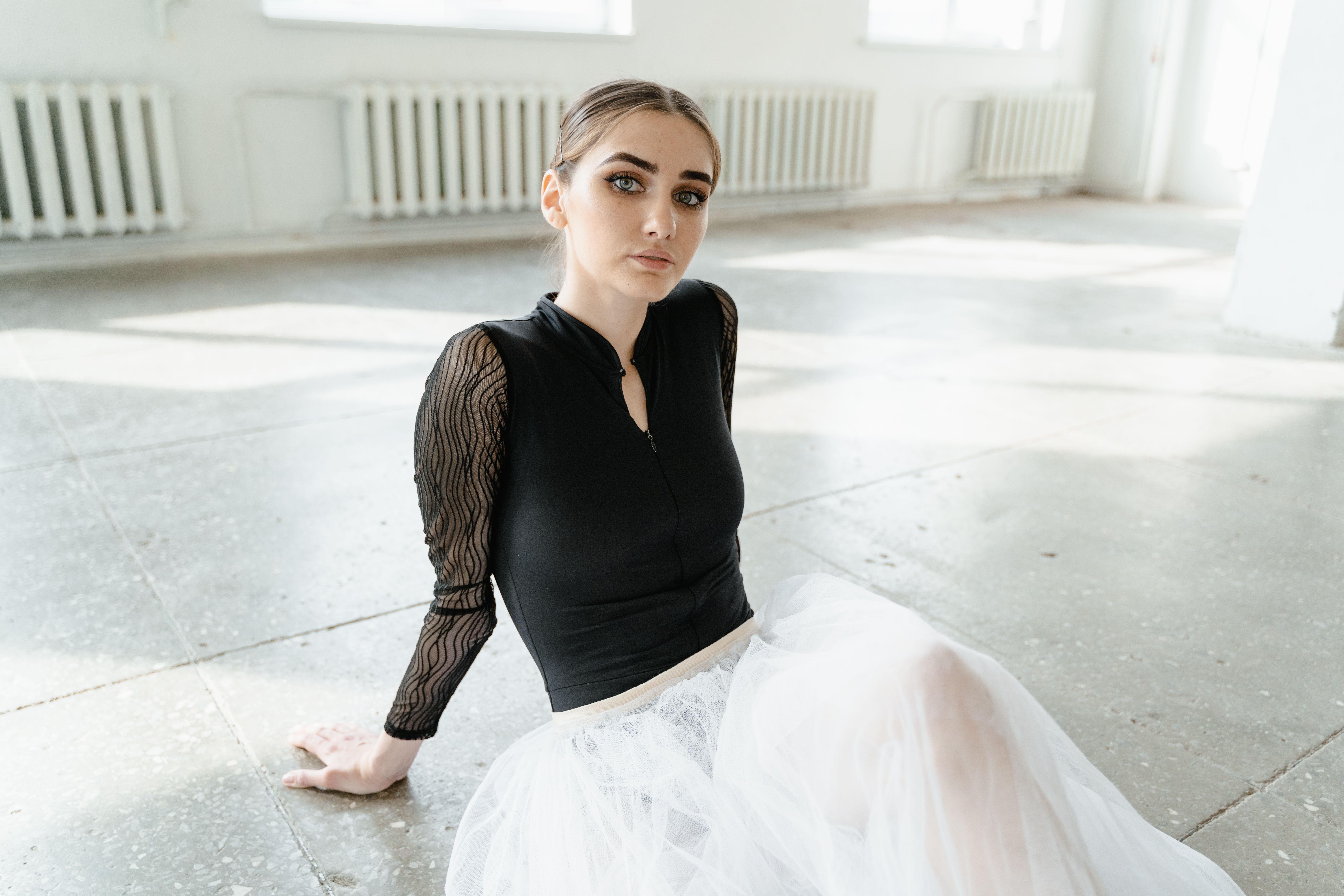 Woman in Black Long Sleeve Shirt and White Skirt Sitting on Concrete ...