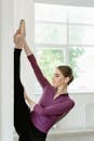 Woman in Purple Long Sleeve Shirt Leaning on White Window