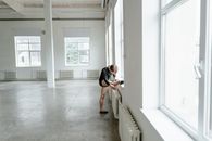 Woman in Black T-shirt and White Pants Sitting on White Wooden Bench
