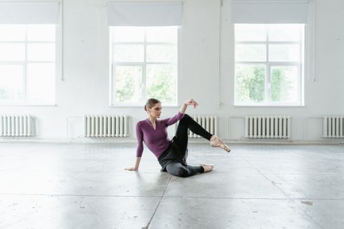 Free Ballerina sitting gracefully on studio floor, exuding poise and elegance. Stock Photo