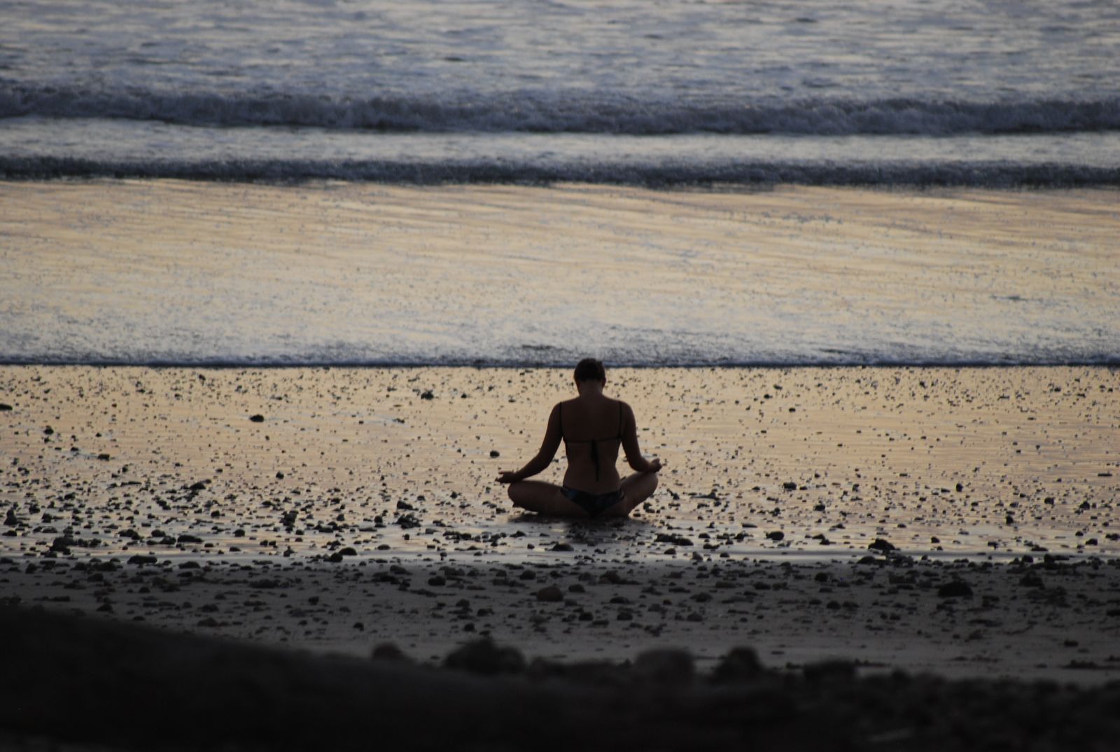 Person practicing yoga on the beach at golden hour