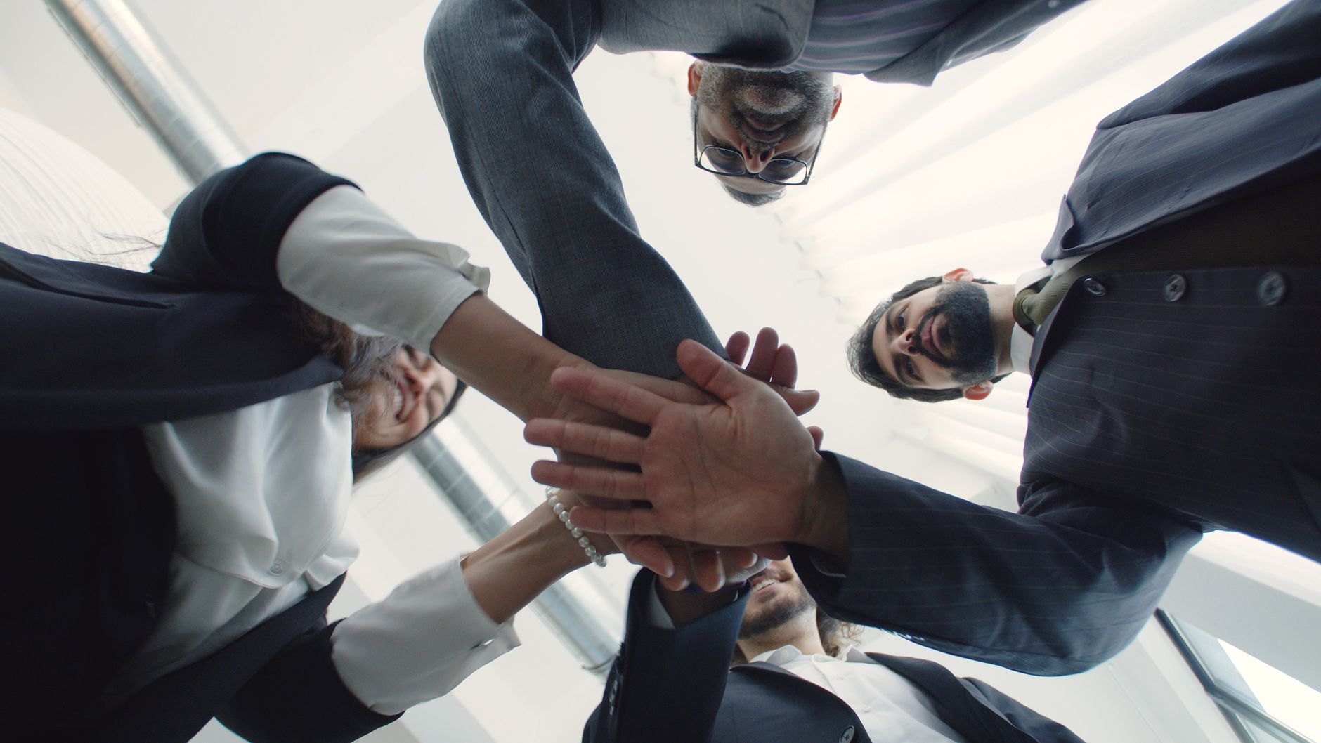 Modern bir ofis ortamında uyum içinde çalışan, birbirine destek olan gülümseyen iş profesyonelleri ve ekip ruhunu simgeleyen iş birliği görüntüsü.