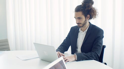 Man in a Suit Typing on His Laptop