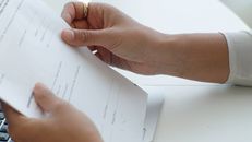 Person Wearing Gold Ring Holding White Paper
