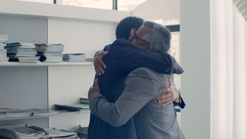 Two colleagues sharing a warm hug in a sunlit office — photo by Kampus Production on Pexels
