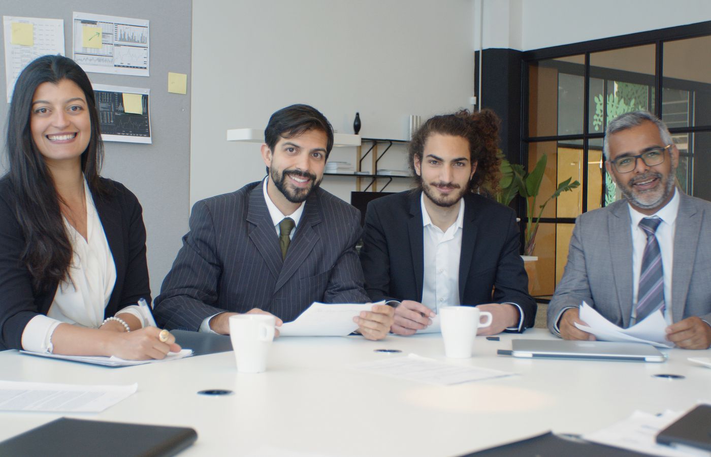 A diverse group of business professionals having a meeting in a modern office setting, engaged and smiling.