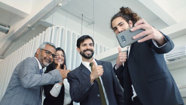 A group of diverse business colleagues taking a cheerful selfie indoors.
