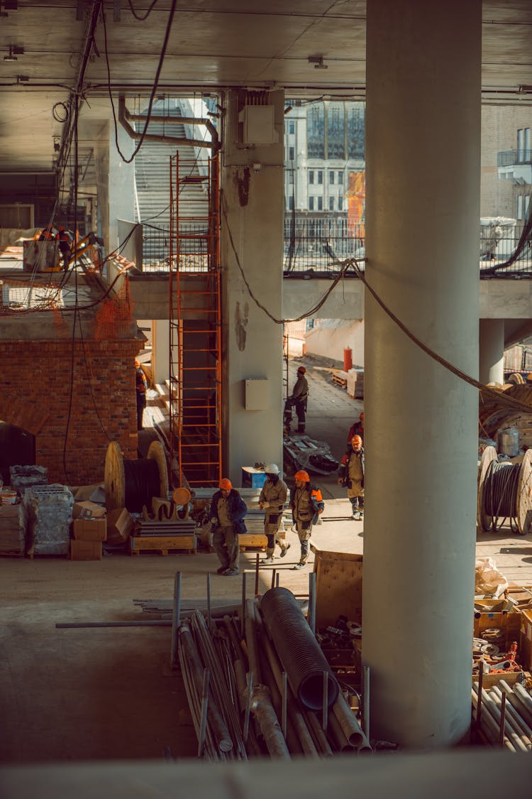 Workers Wearing Hard Hats While Walking Inside A Building