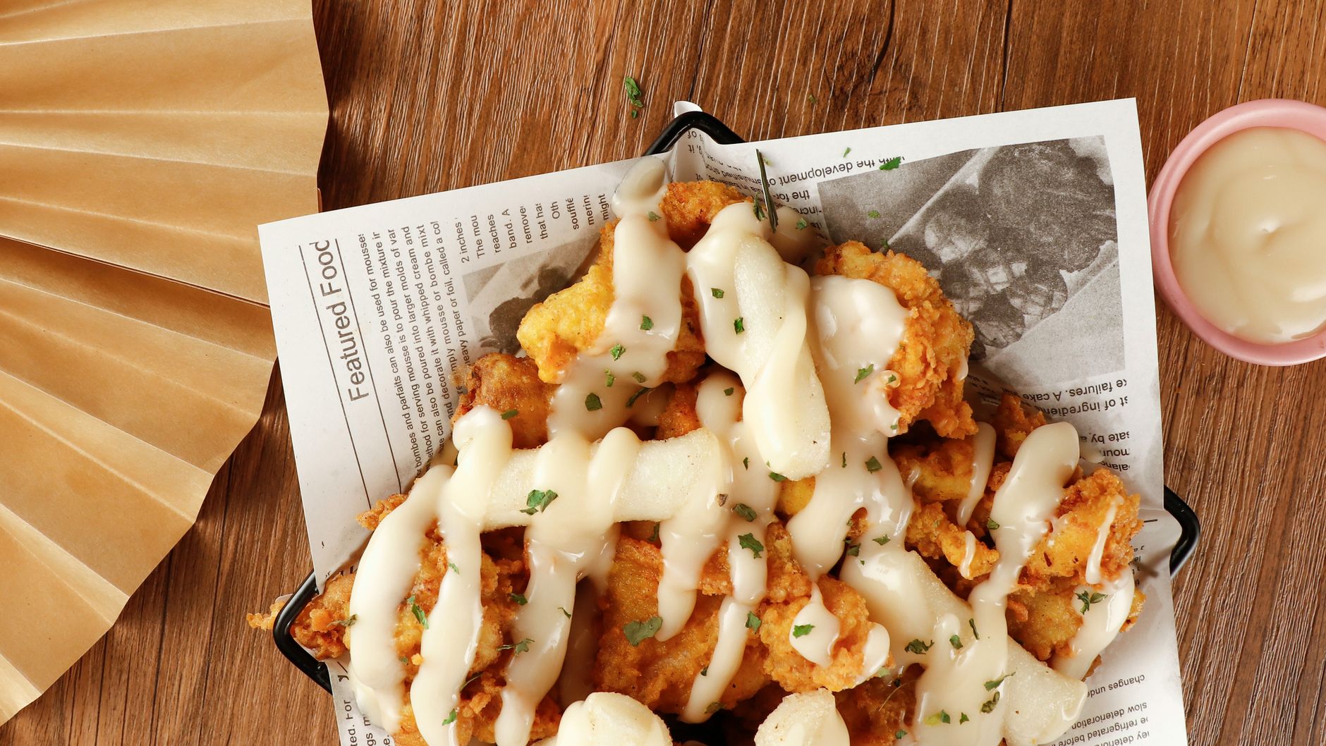 Delicious crispy fried chicken with creamy sauce served on a rustic wooden table.