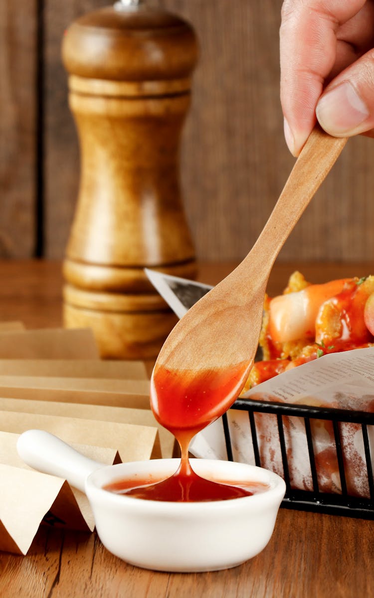 Person Dipping A Spoon In Sauce 