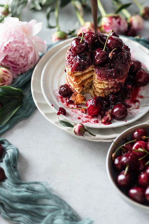 Free Delicious cherry-topped pancakes styled with peonies for a rustic brunch setting. Stock Photo