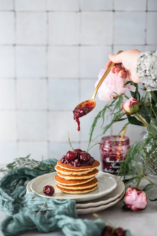 A Person Putting Jam on Pancakes 