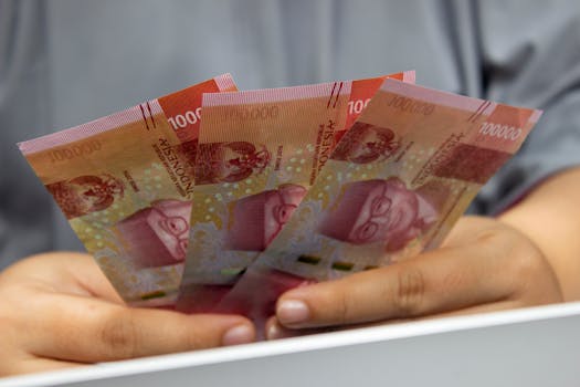 Hands holding multiple Indonesian Rupiah banknotes, showcasing currency details.