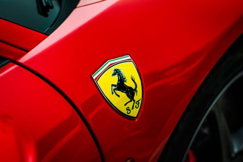 Free Detailed view of a luxury car emblem on a sleek red sports car, showcasing elegance and style. Stock Photo