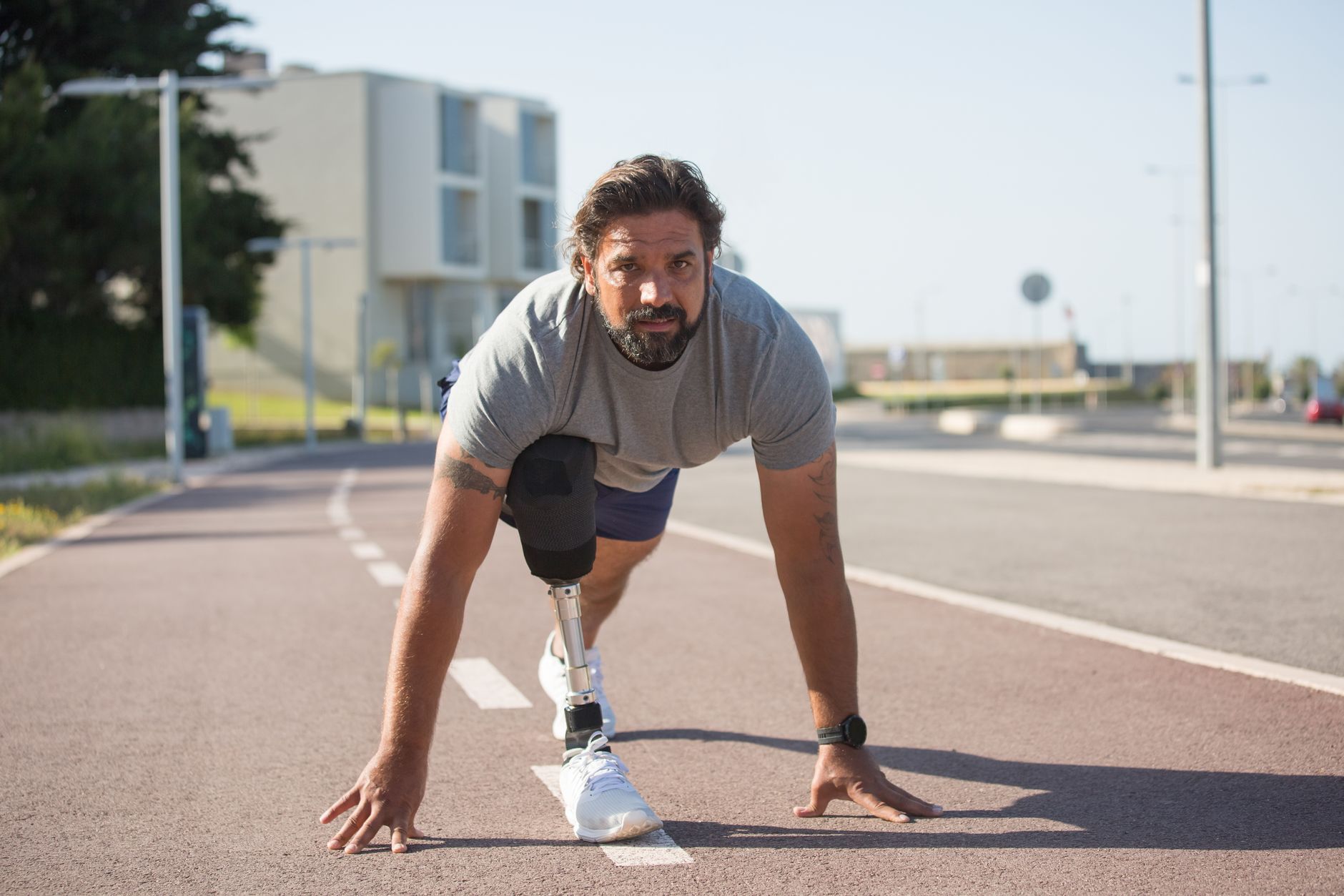 心理健康的每日5分鐘習慣養成法:簡單實踐大改變 A determined man with a prosthetic leg prepares to run on an urban track, showcasing resilience.