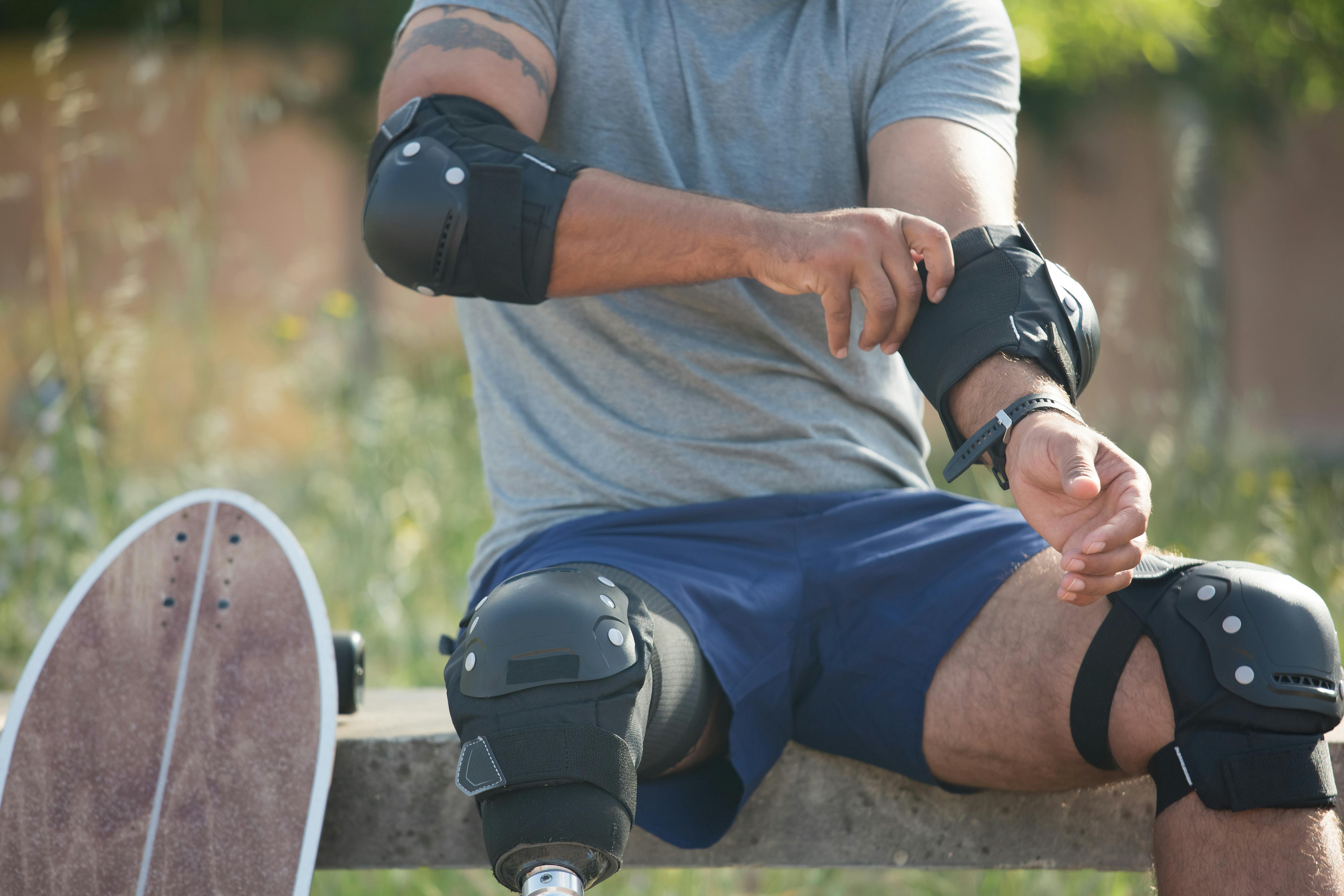 Skateboarder with prosthetic leg adjusts safety gear outdoors in Portugal.
