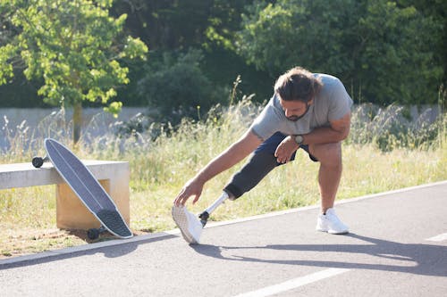 Man with Prosthetic Leg Stretching Before Longboarding