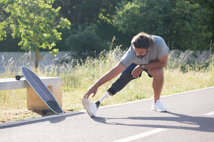 Man With Prosthetic Leg Stretching Before Longboarding