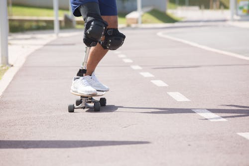 A Person with Knee Pads Skateboarding on Road