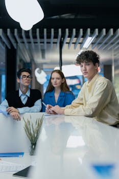 Group of young professionals collaborating at a desk in a modern office setting, showcasing teamwork.