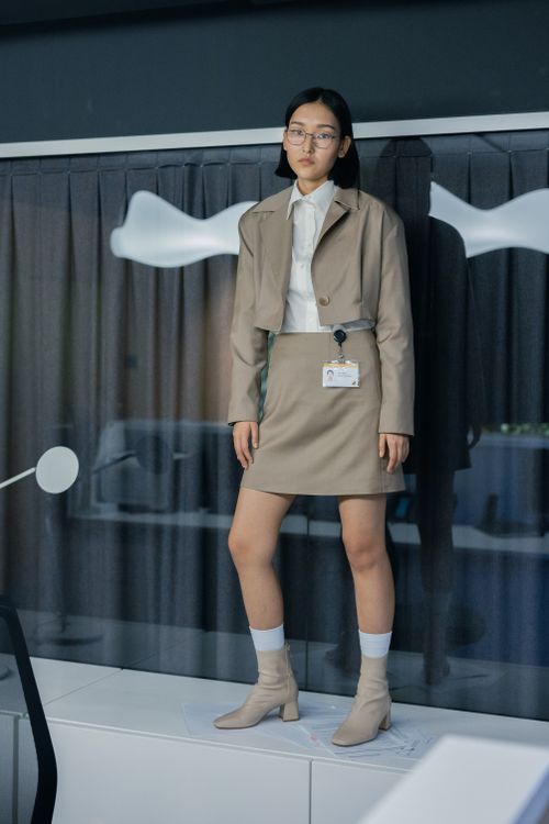 Free Asian woman in formal attire standing confidently, reflecting on glass window. Stock Photo