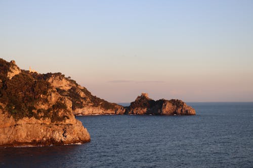 A Rock Formation Near the Body of Water Under the Clear Sky