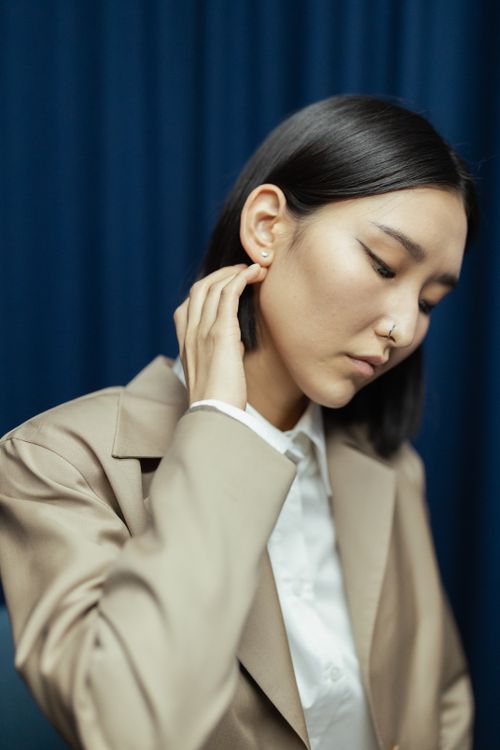 Free Professional portrait of a stylish woman in business attire posing against a blue backdrop. Stock Photo