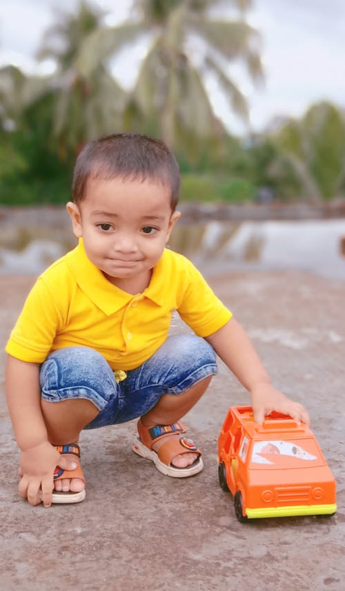 A Boy in Yellow Polo Shirt Playing a Toy Car