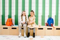 2 Women Sitting on Brown Wooden Bench