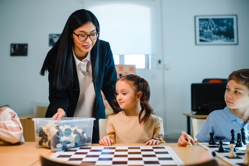 Free Teacher instructing young students in chess at school, enhancing critical thinking. Stock Photo