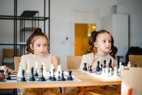 Identical Twins Sisters Playing Chess Together 