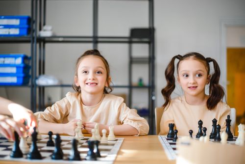 Free Two young girls enjoy a game of chess, focusing on strategy and fun. Stock Photo