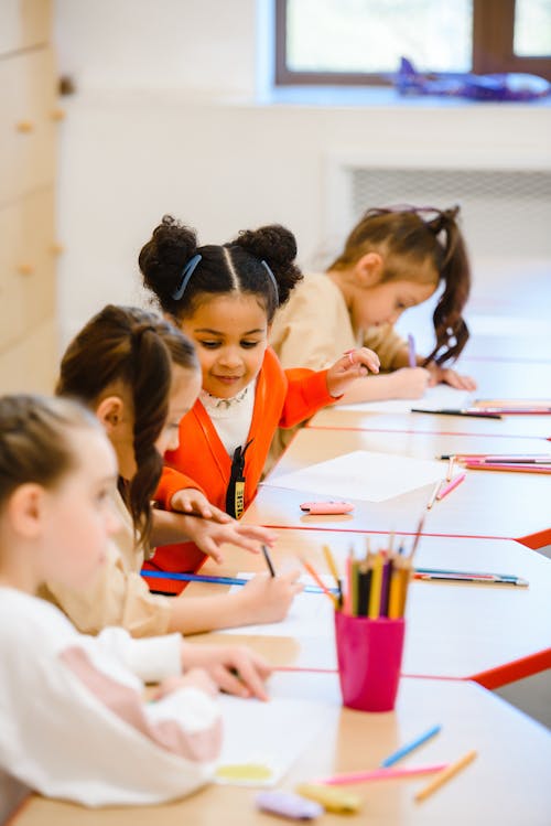 Free Children Coloring on Tables  in a Room Stock Photo