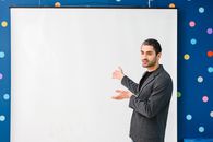 Man in Black Blazer Standing Beside White Wall