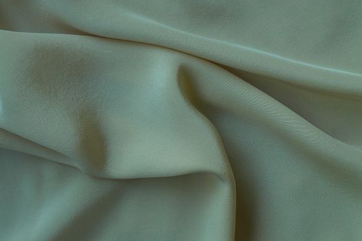 Detailed close-up shot of soft, smooth green velvet fabric with gentle folds.