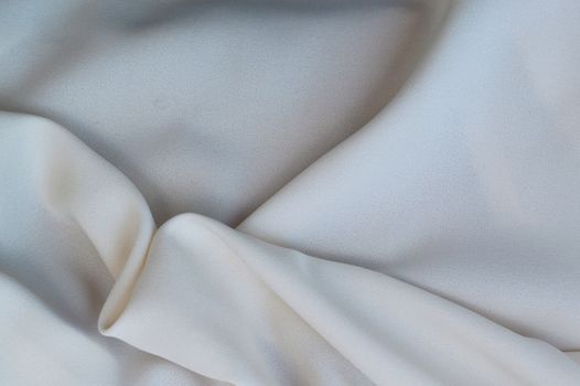 Close-up of soft white silk fabric with gentle folds, creating a delicate and smooth texture.