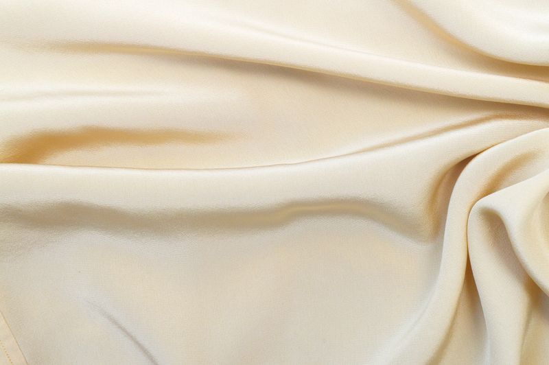 Elegantly draped beige fabric creating graceful folds and a soft texture